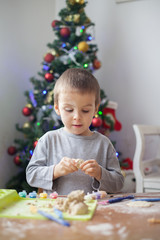 Cute little boy, playing with modeling dough, molding figures at home on Christmas 