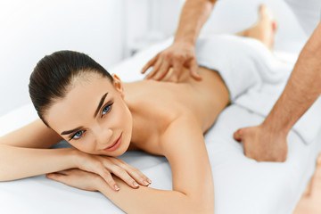 Fototapeta na wymiar Spa Woman. Beauty Treatment. Beautiful Young Healthy Caucasian girl relaxing with hand Massage Procedure In The Spa Salon. Masseur Massaging her Back. Body Care. Skin Care, Wellness, Wellbeing.