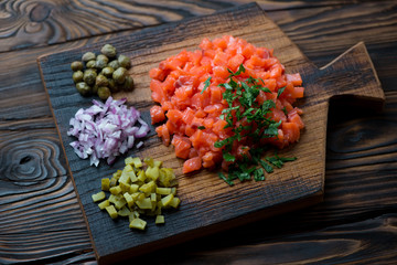 Wooden rustic cutting board with salmon tartare, studio shot