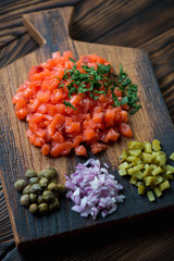 Salmon tartare with parsley, capers, onion and pickles, close-up