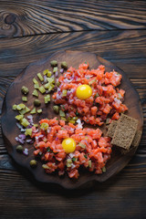 Salmon tartar on a dark rustic wooden background, above view