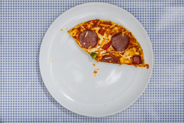 Angeschnittene Pizza Salami, auf blau kariertem Untergrund, Bild