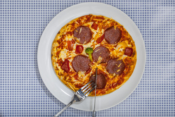Pizza Salami mit Besteck, auf blau kariertem Untergrund, Bilder