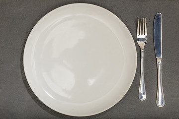 Empty plate and silveware on slate background