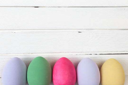Easter eggs painted in pastel colors on white wooden background