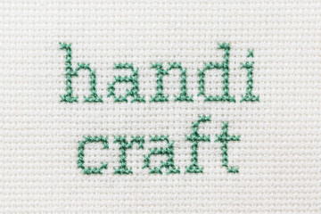 embroidered inscription cross threads on the white  fabric. Handicraft.  A series of embroidered words