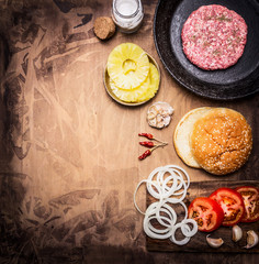 Ingredients for cooking homemade burger, tomatoes, onion rings, burger buns border ,place for text on wooden rustic background top view close up