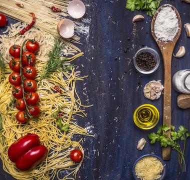 various raw pasta with vegetables and spices, flour and wooden spoon frame with text area on wooden rustic background top view