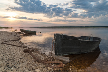 Two laid up wooden boats against Severnaya Dvina River panorama at sunset. Bereznik settlement, Arkangelsky region, Russia.
