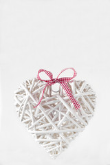 White heart made of  branches with a red ribbon