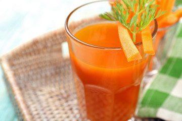 Glass of carrot juice with vegetable slices on table close up
