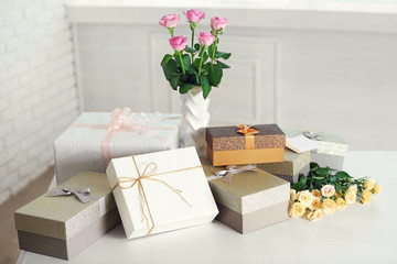 Composition of cute gift boxes and roses on white table
