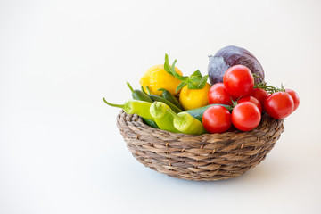 Vegetables in a wicker basket isolated on white background