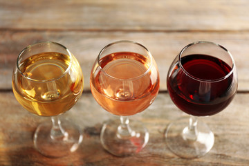 Glasses with white, rose and red wine on wooden background
