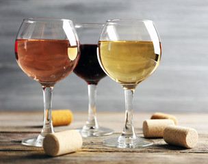 Composition of wine glasses and corks on wooden table against grey background