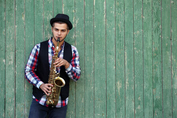 The musician plays saxophone on green wooden background