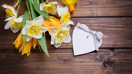 Background with fresh daffodils and tulips and decorative heart