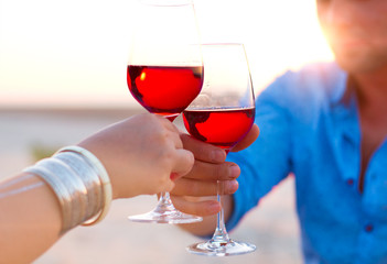 Close-up of two human’s hand with wineglasses red wine during