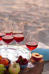 Glasses of the red wine on the sunset beach