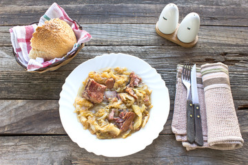 Sauerkraut with smoked pork meat on wooden background