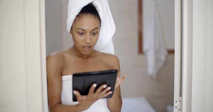 Young Woman Wearing Bath Towel Using Tablet Computer