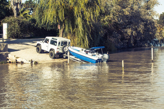 All terrain vehicle towing a trailer with a boat on top into the water.
