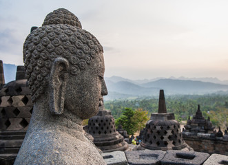 Stone Buddha on stone background stupas. Borobudur. Indonesia. The island of Java. An excellent illustration.