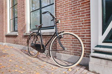 Fototapeta na wymiar Classic Dutch bicycle parked against a brick wall in autumn, Amsterdam, The Netherlands