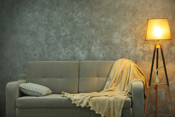 Comfortable sofa and lamp on grey wall background