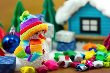 Snowman and gift box with small star paper on the snow field.