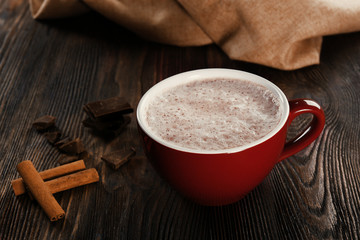 Cup of hot cacao with cinnamon and sweets on wooden background, close up