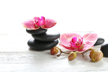 Beautiful composition of orchid and pebbles on white wooden background