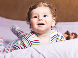 Beautiful baby with a lovely toy. The child in the crib.
