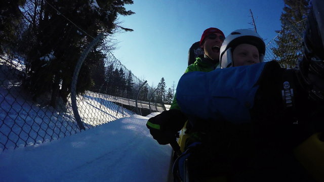 father and son ehjoying winter bobsleigh attraction