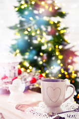 Mug with hot drink and Christmas decorations on fir tree background