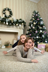 Fototapeta na wymiar mother and daughter are dreaming near Christmas tree. Family holiday 