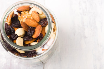 Jar filled with mixed nuts and raisin on a white wooden vintage table