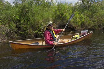 Senior man paddling a small canoe on the Moose River in the Adirondacks, New York.