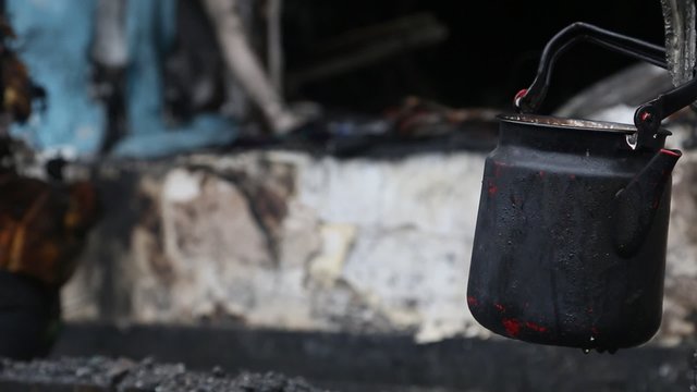 Black kettle on a charred ruins in burnt building
