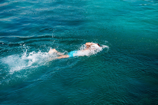 Single swimmer swimming in blue clear water