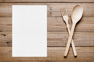 Paper sheet and wooden fork and spoon on table top view