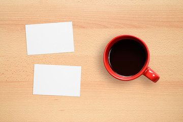 Two business cards and coffee cup on office desk