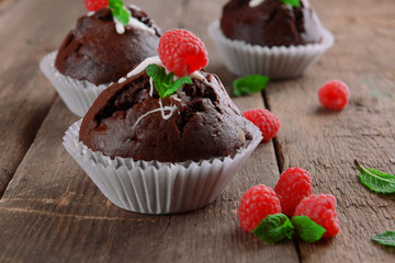 Delicious chocolate cupcakes with berries and fresh mint on wooden table close up