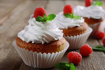Delicious cupcakes with berries and fresh mint on wooden table close up