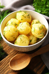 Boiled potatoes with greens in bowl on table close up