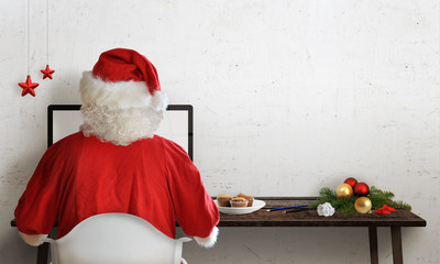 Santa Claus responds to letters on a computer for Christmas.