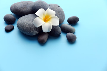 Obraz na płótnie Canvas Spa stones with flower on blue background