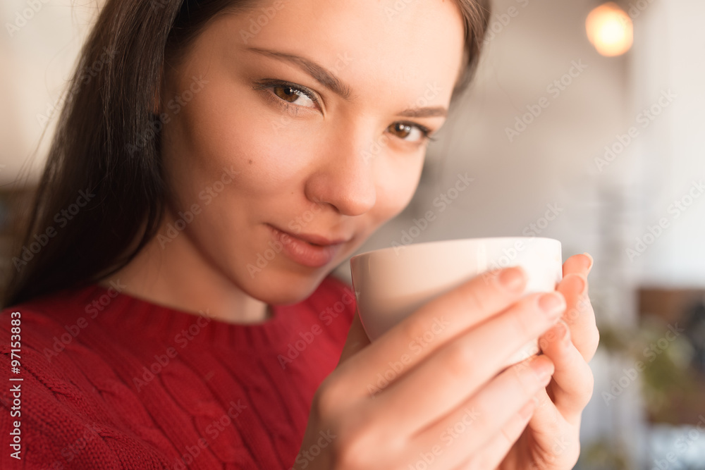 Wall mural a young woman sitting in a coffee shop with cup