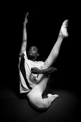 Classical ballet dancer warming up with stretches in black and white