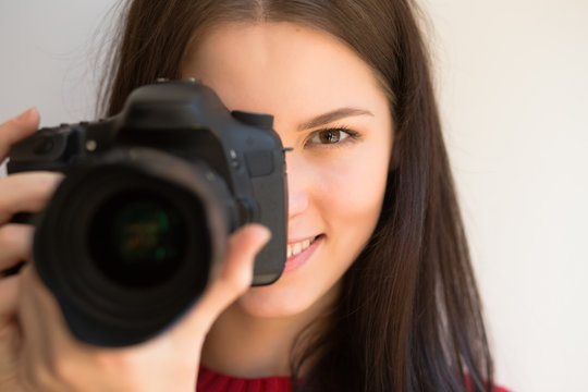 Cute girl photographer taking pictures and smiling with camera